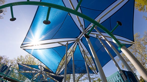 Sun shining through a blue hexagonal SkyWays® shade structure.