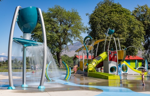 A splash pad with a blue overhead dumping bucket and large multi-faceted water play structure