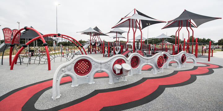 A full view of the playground at Jonesboro Miracle League Park with sensory panel learning wall in foreground. 