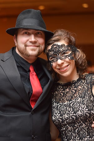A man and women smile while dressed up at a holiday party.