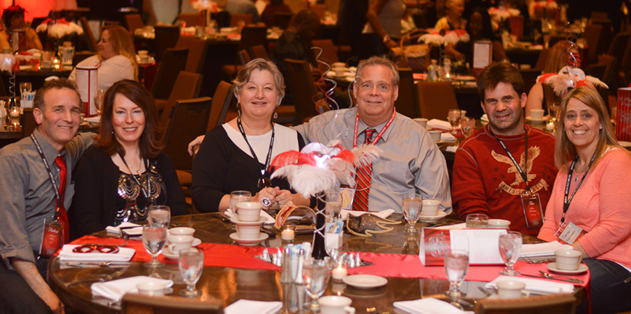 Landscape Structures employees smile for the camera while sitting at a table darning a holiday party.