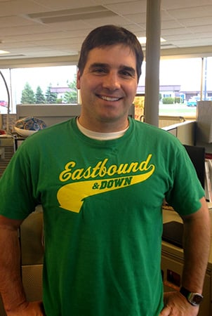Landscape Structures Brock Suska smiles for the camera while wearing a Eastbound and Down t-shirt.