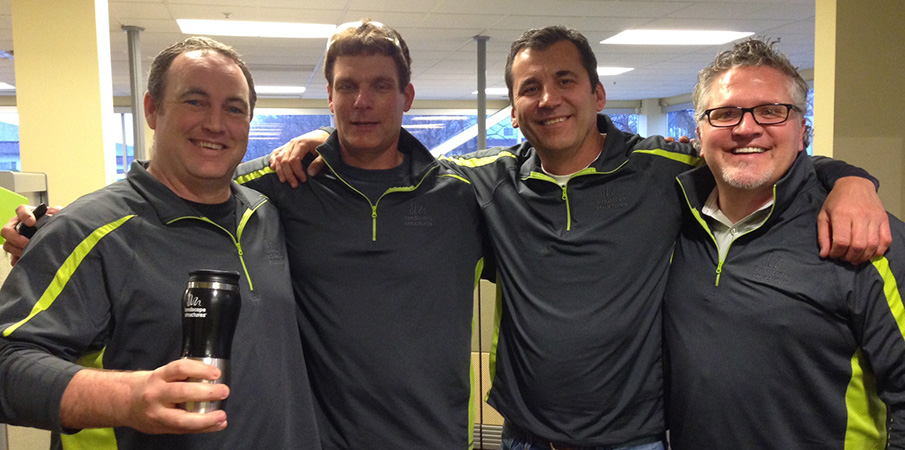 President Pat Faust stands with three other Landscape Structures employees in matching sweatshirts.