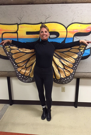 Landscape Structures Karen Miller holds her arms up to show how her costume monarch butterfly wings.