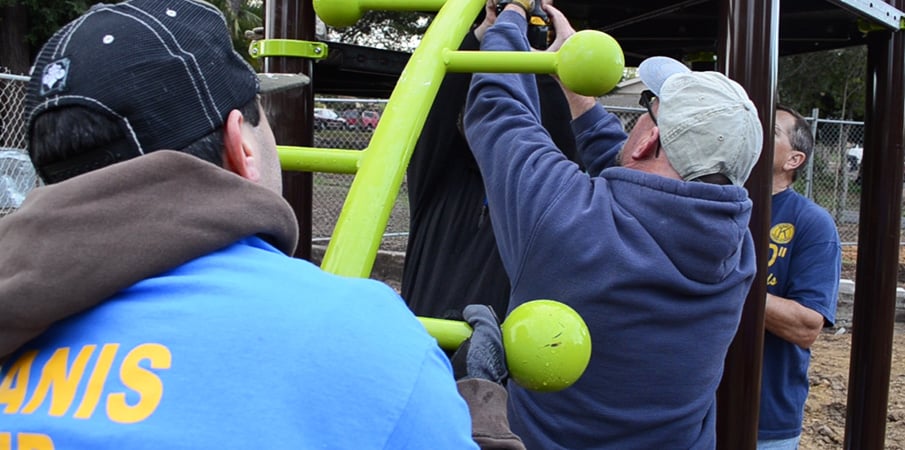 Volunteers attaching Lollipop Climber to playground decking.
