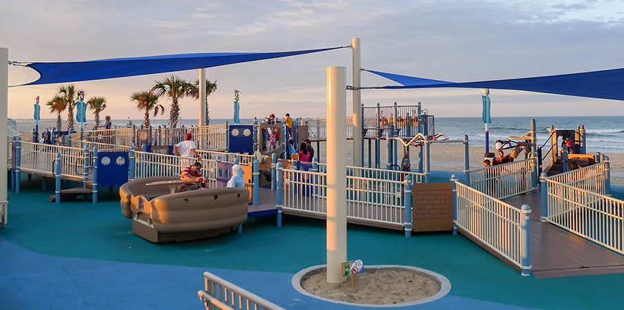 A inclusive playground set next to a ocean beach.