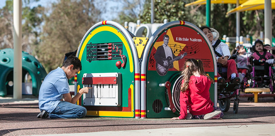 Children play on reach music play panels. 